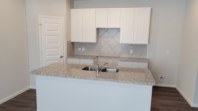 kitchen featuring dark hardwood / wood-style floors, an island with sink, sink, white cabinetry, and light stone counters