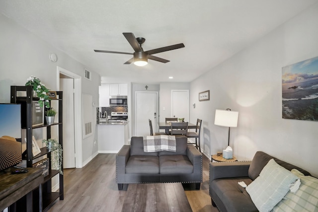 living room featuring light hardwood / wood-style floors, sink, and ceiling fan