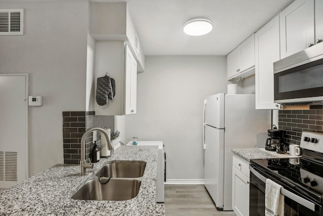 kitchen featuring light stone countertops, sink, white cabinetry, stainless steel appliances, and decorative backsplash