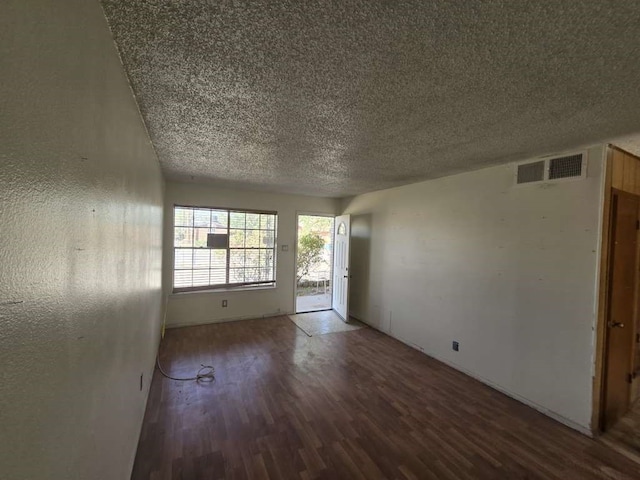 unfurnished room with a textured ceiling and dark hardwood / wood-style floors