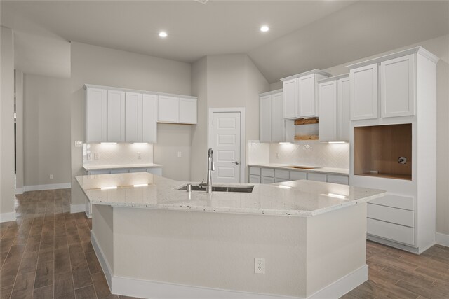 kitchen featuring a large island with sink, sink, vaulted ceiling, white cabinets, and dark hardwood / wood-style flooring