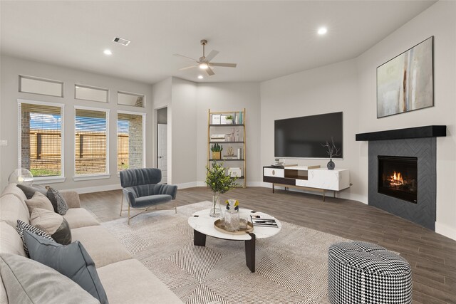 living room with hardwood / wood-style flooring, ceiling fan, and a tile fireplace