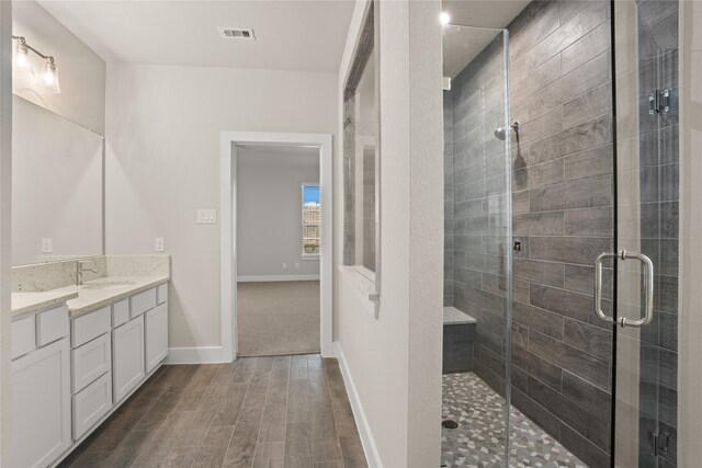 bathroom featuring walk in shower, vanity, and wood-type flooring