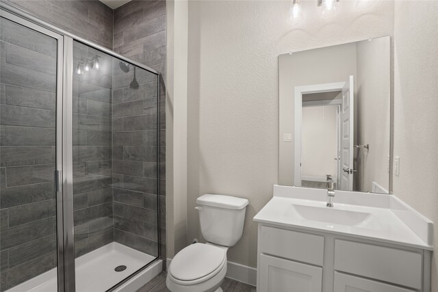 bathroom with toilet, vanity, and a shower with shower door