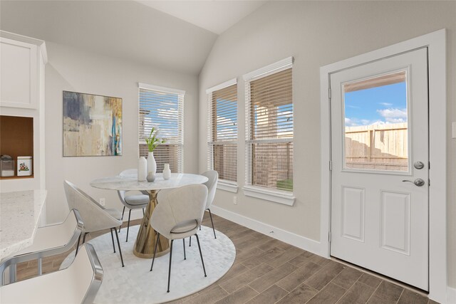 dining space with vaulted ceiling, plenty of natural light, and dark hardwood / wood-style flooring