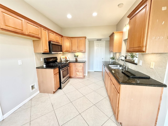 kitchen with sink, decorative backsplash, dark stone countertops, light tile patterned floors, and stainless steel appliances