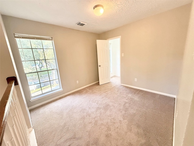 carpeted spare room featuring a textured ceiling