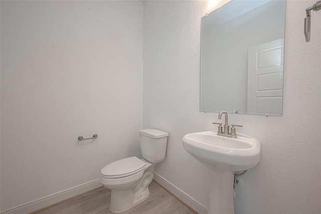 bathroom featuring toilet, hardwood / wood-style floors, and sink