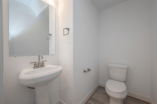 bathroom with toilet, sink, and hardwood / wood-style floors