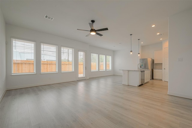 unfurnished living room with ceiling fan, light hardwood / wood-style floors, and sink