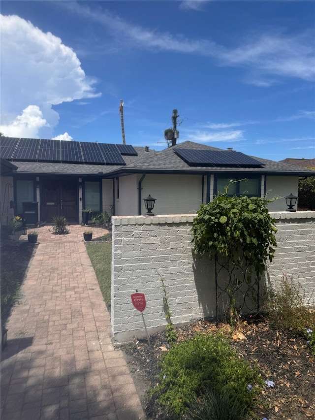 back of property featuring roof mounted solar panels and roof with shingles