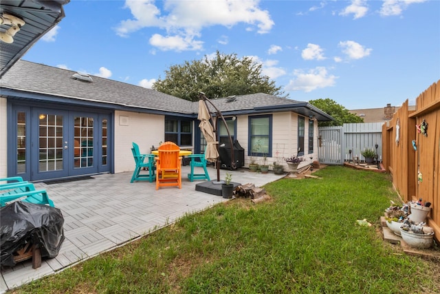 back of property featuring a yard, a fenced backyard, a shingled roof, french doors, and a patio area