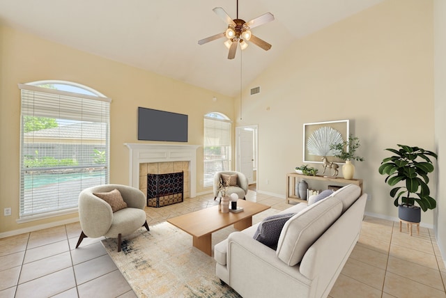 tiled living room with a tile fireplace, high vaulted ceiling, and ceiling fan