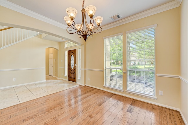 interior space with a chandelier, ornamental molding, and light hardwood / wood-style flooring