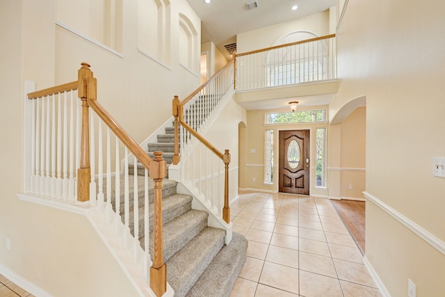 entryway featuring a towering ceiling and light tile patterned floors