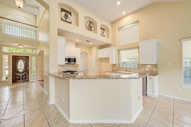 kitchen featuring white cabinets, light tile patterned flooring, light stone countertops, and decorative backsplash