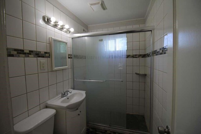 1507 Demaree Ln, Houston, TX 77029 - bathroom with a shower stall, toilet, crown molding, vanity, and tile walls