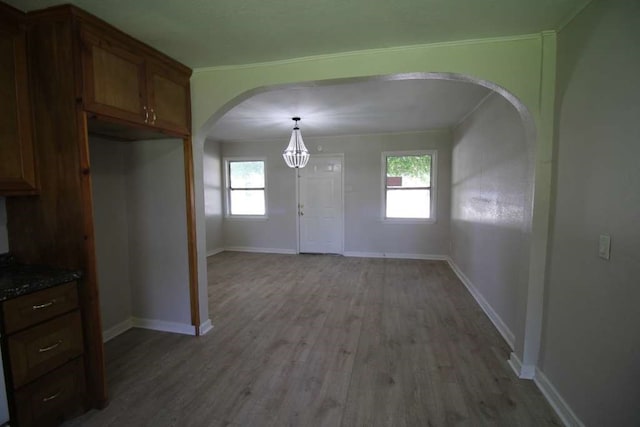 unfurnished dining area with a healthy amount of sunlight, a notable chandelier, and hardwood / wood-style flooring