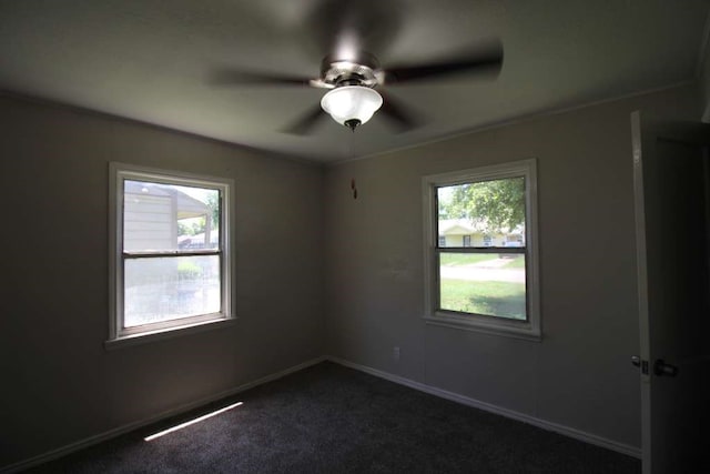 unfurnished room featuring a wealth of natural light, dark carpet, and ceiling fan