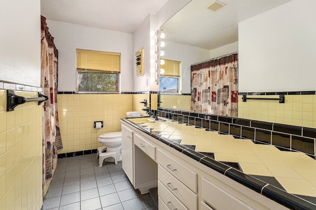 bathroom featuring tile patterned floors, toilet, tile walls, decorative backsplash, and vanity