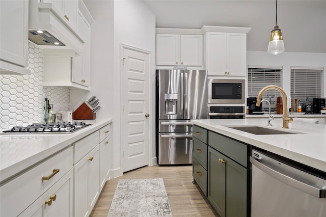 kitchen featuring custom range hood, hanging light fixtures, stainless steel appliances, sink, and white cabinets