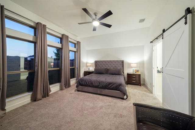 carpeted bedroom with a barn door and ceiling fan