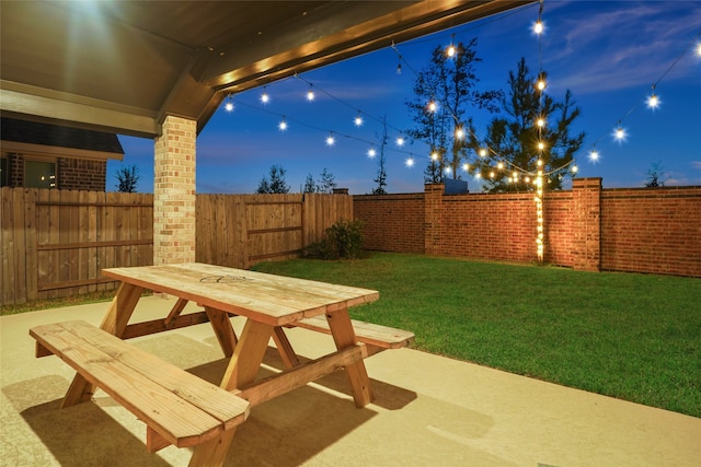 patio at night featuring a lawn