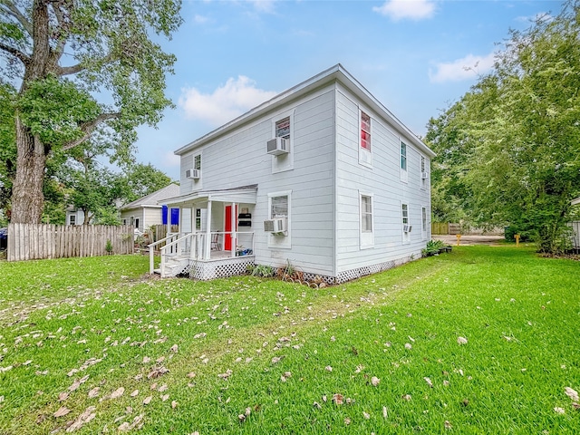 rear view of house featuring a lawn and cooling unit