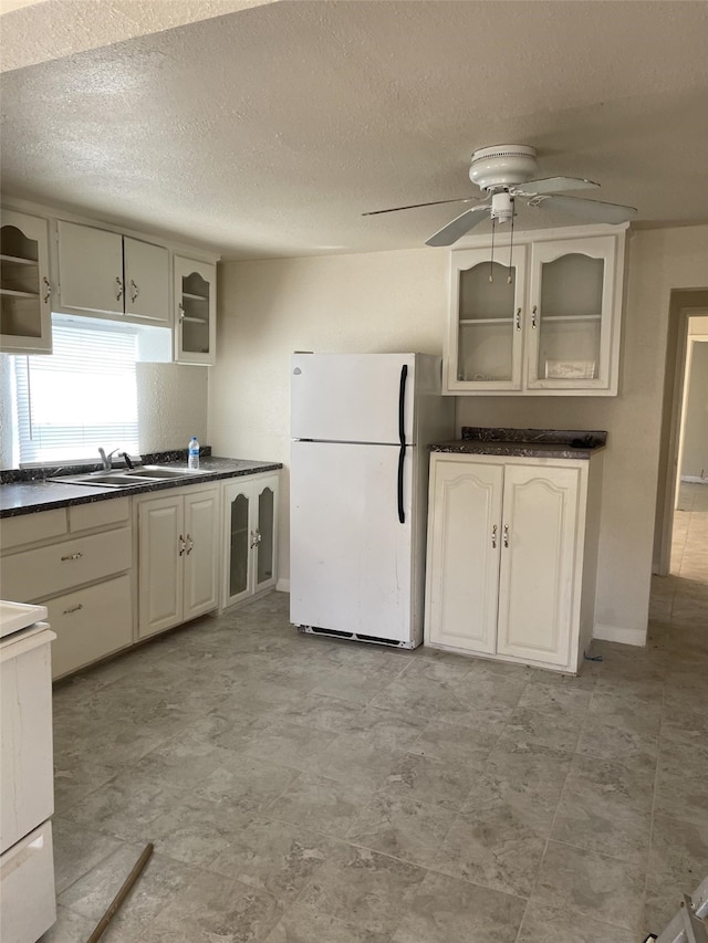 kitchen featuring white appliances, sink, ceiling fan, and a textured ceiling