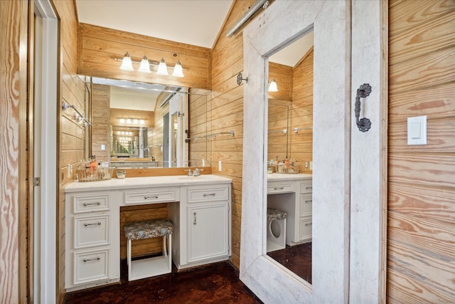 bathroom featuring vanity, vaulted ceiling, and wood walls