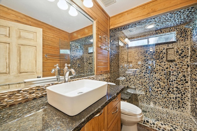 bathroom featuring vanity, wooden walls, and toilet