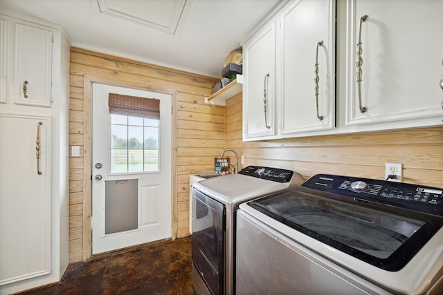 washroom featuring cabinets, sink, wooden walls, and washing machine and dryer