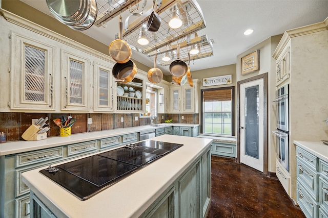 kitchen with decorative backsplash, appliances with stainless steel finishes, sink, a kitchen island, and hanging light fixtures