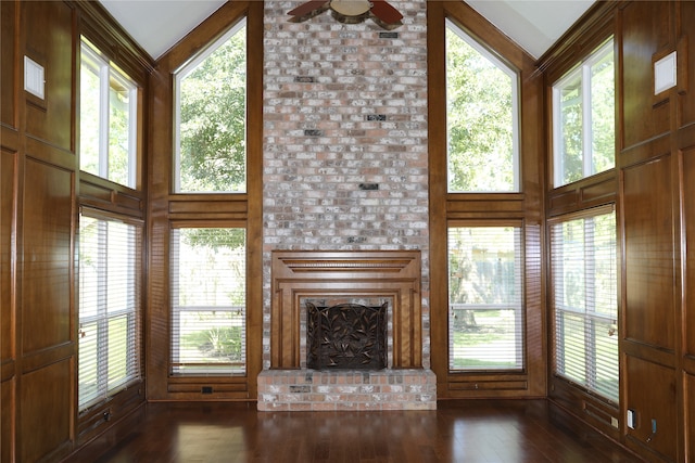 unfurnished living room featuring ceiling fan, dark hardwood / wood-style floors, high vaulted ceiling, and a brick fireplace