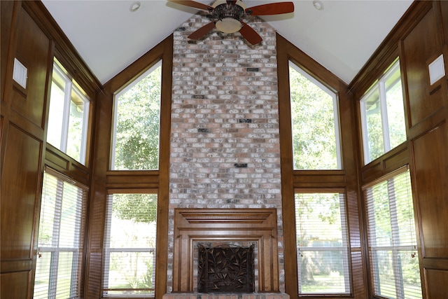 unfurnished living room featuring high vaulted ceiling, a brick fireplace, and plenty of natural light