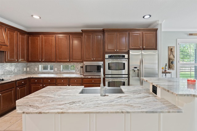 kitchen featuring a center island with sink, light tile patterned floors, decorative backsplash, appliances with stainless steel finishes, and a sink