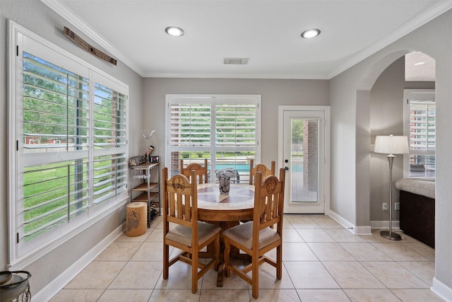 dining room featuring arched walkways, visible vents, light tile patterned floors, and ornamental molding