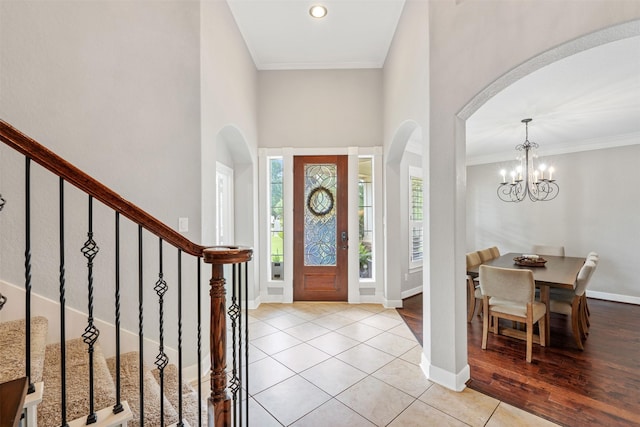 tiled foyer with a notable chandelier, baseboards, arched walkways, and ornamental molding