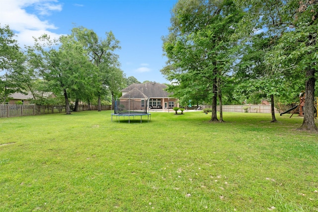 view of yard featuring a trampoline, a fenced backyard, and a playground