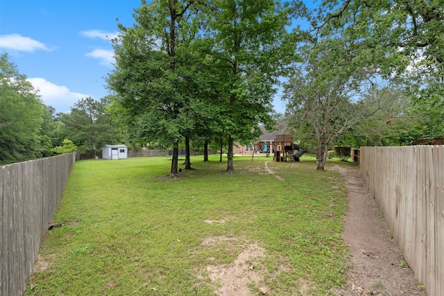 view of yard with an outbuilding, a storage shed, a fenced backyard, and a playground