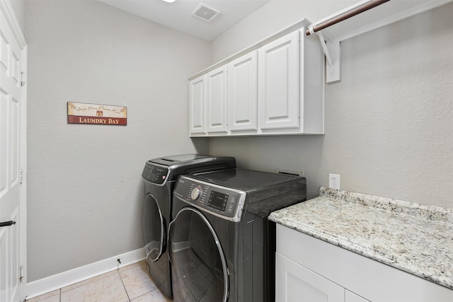 clothes washing area with visible vents, washer and dryer, cabinet space, light tile patterned flooring, and baseboards