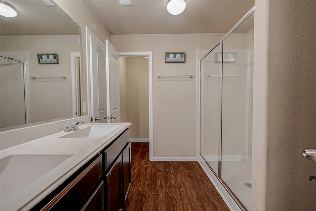 bathroom with hardwood / wood-style floors, vanity, and a shower with shower door