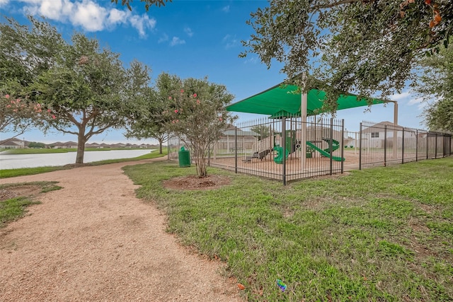 community playground featuring a water view, fence, and a lawn