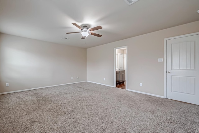 unfurnished room with a ceiling fan, visible vents, dark carpet, and baseboards