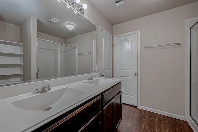 full bath with visible vents, a sink, a shower with door, and wood finished floors