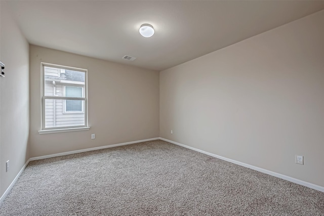 empty room featuring carpet, visible vents, and baseboards