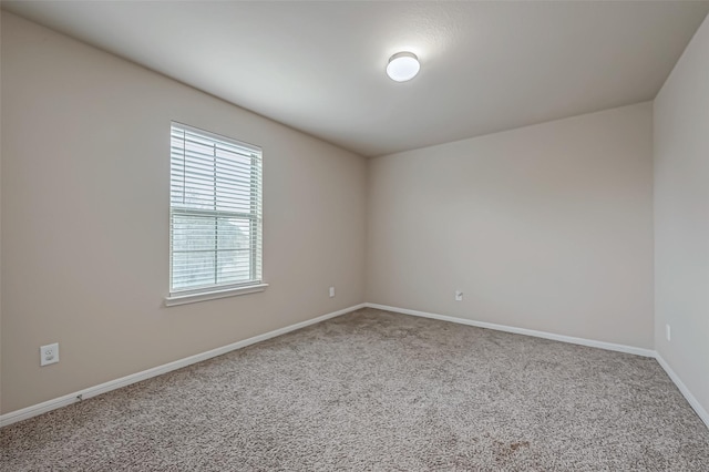 unfurnished room featuring carpet and baseboards