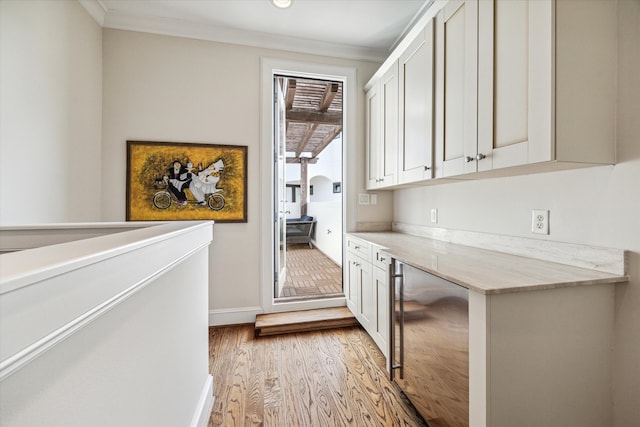 interior space with crown molding, light stone counters, and light hardwood / wood-style floors