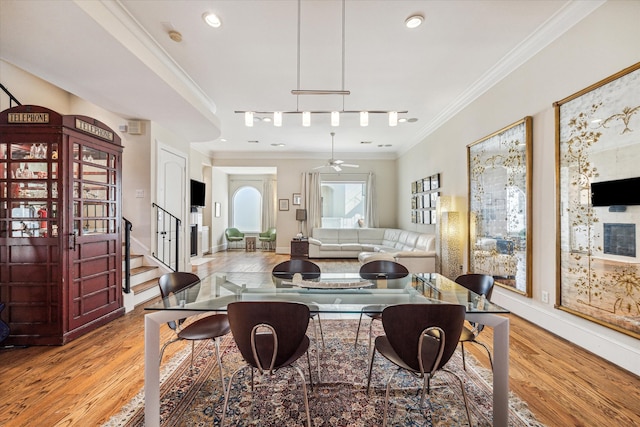 dining room featuring light wood-type flooring, rail lighting, ceiling fan, and crown molding