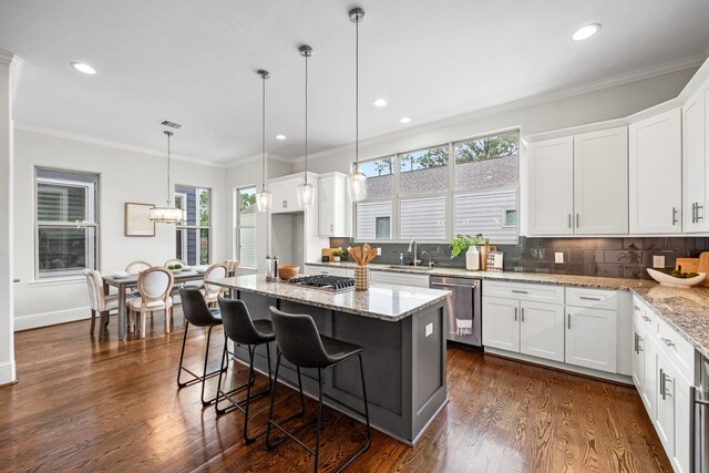 kitchen with appliances with stainless steel finishes, light stone counters, white cabinetry, and a center island